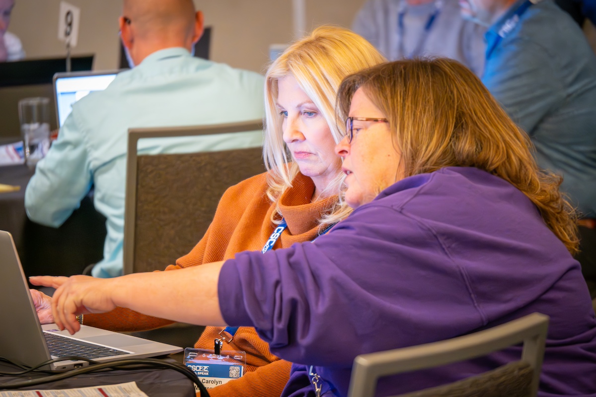 two women working together on a laptop