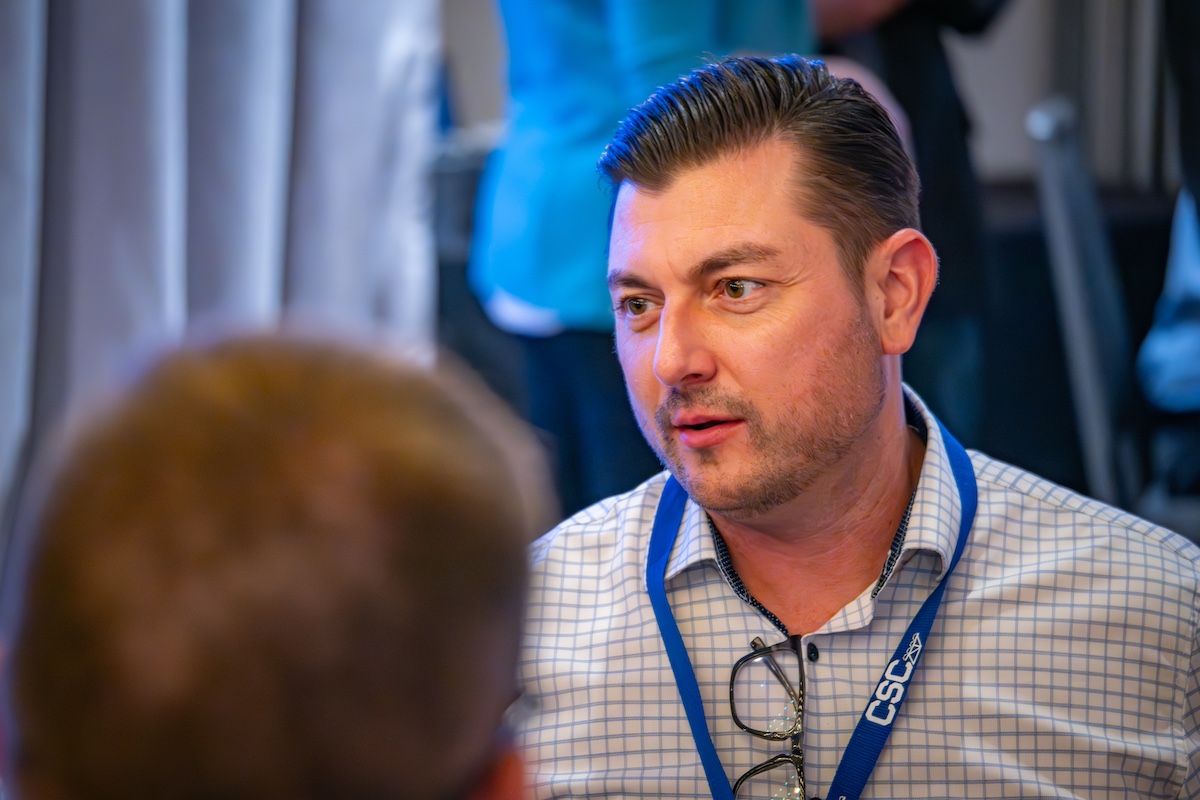 man with a lanyard speaking to an employee
